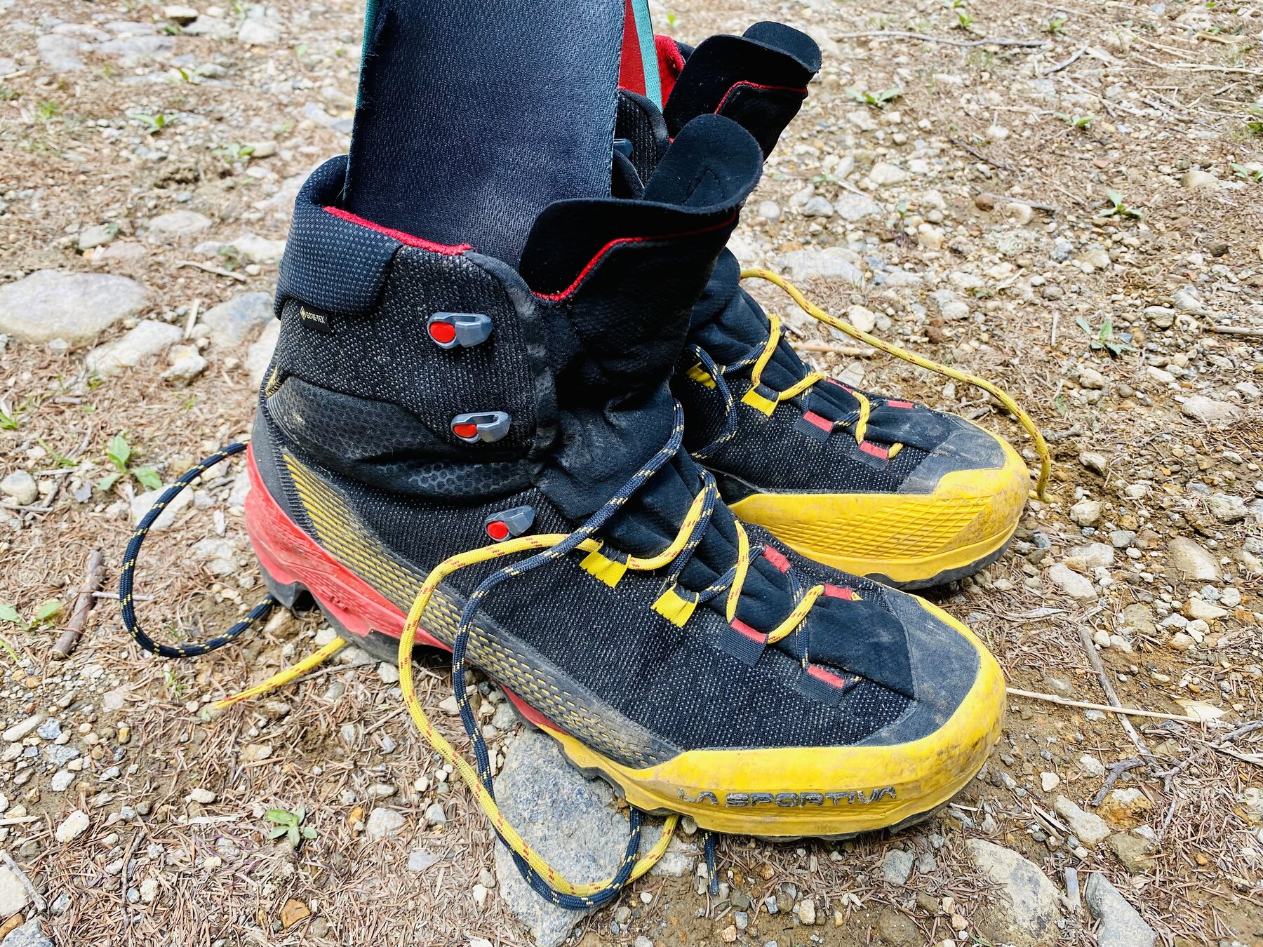 使い込んだスポルティバ エクイリビウム ST GTX。黒のアッパーに黄色いトゥ、赤いミッドソール。靴ひもをほどいて地面に置いた状態