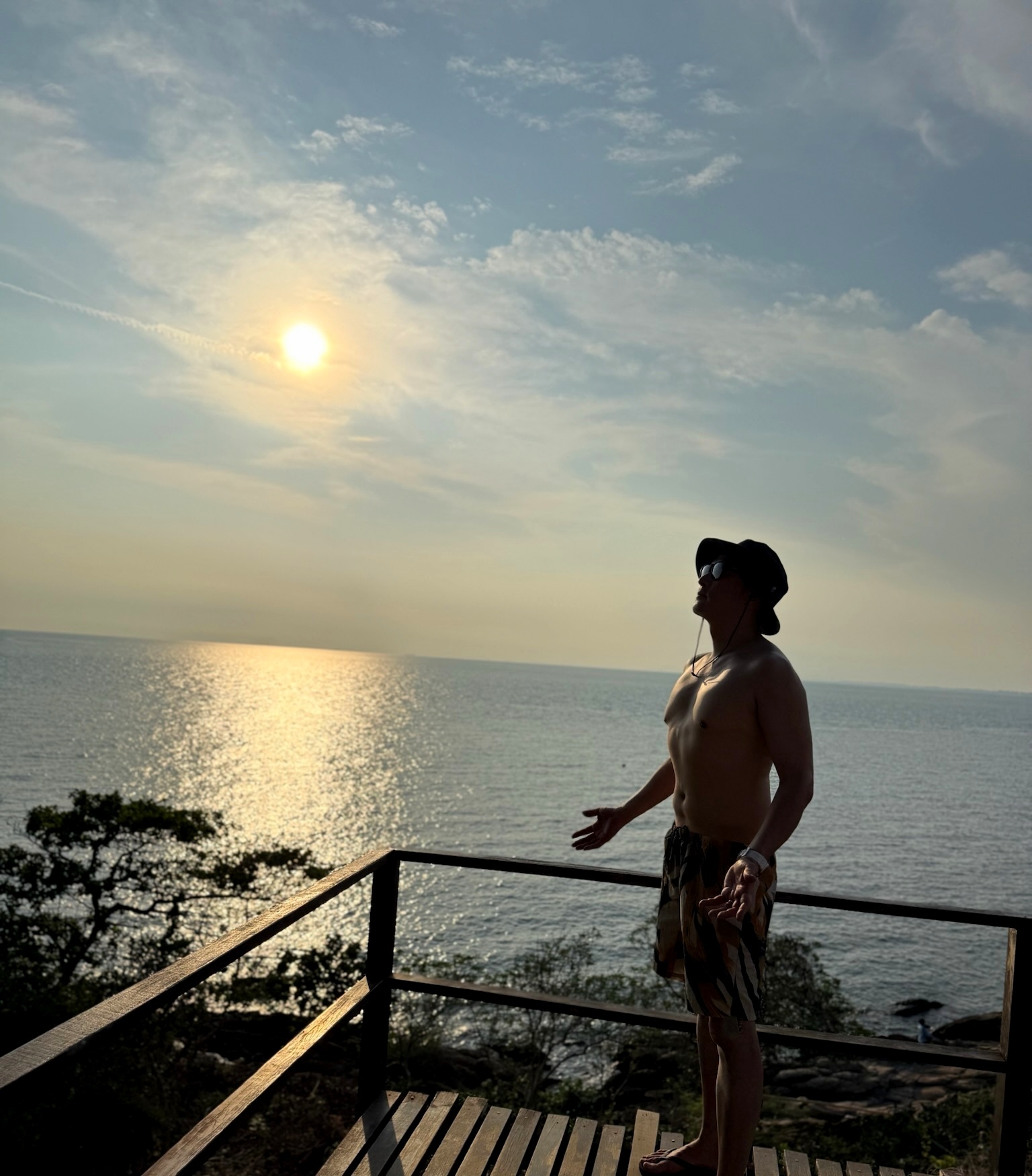 夕方の海を眺める瀬名コサト。逆光でシルエットになっている